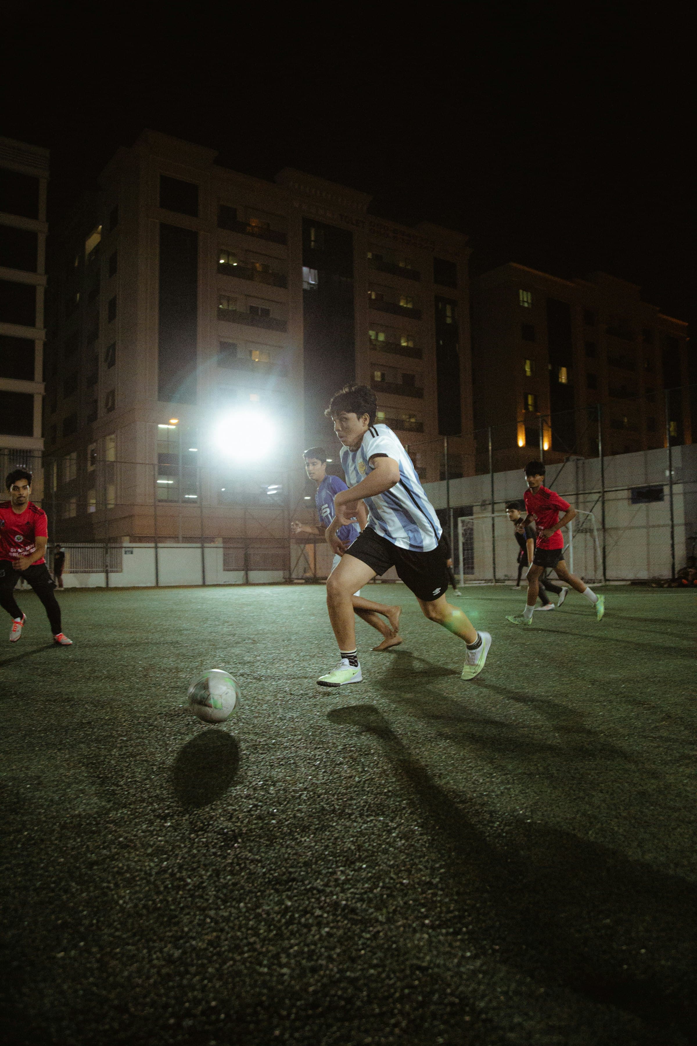 Friends playing street football at night under a floodlight